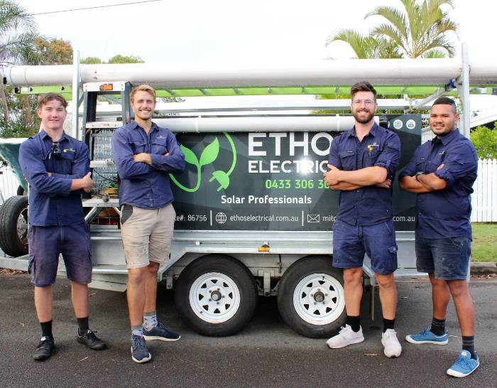 Ethos Electrical team members standing beside their branded equipment trailer