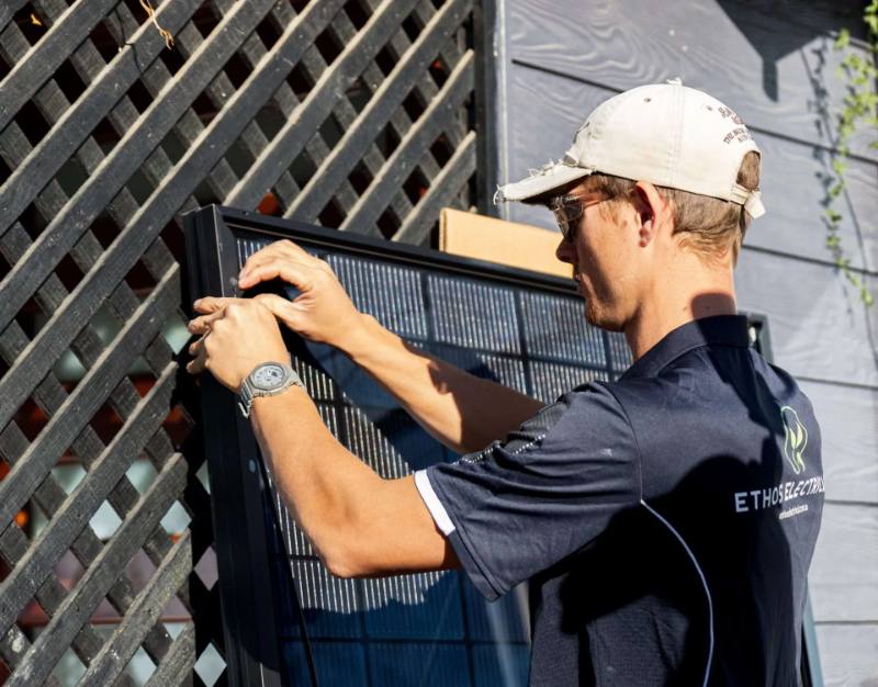 Close-up of an Ethos Electrical technician fitting a solar panel into its mounting rail